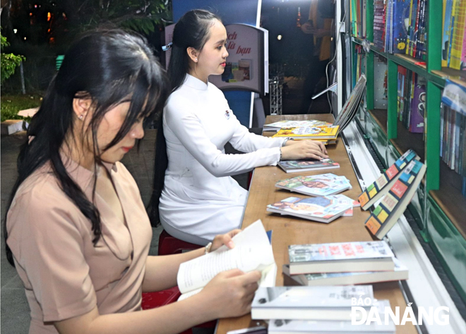 Young people are seen voraciously reading books outside the bookmobile