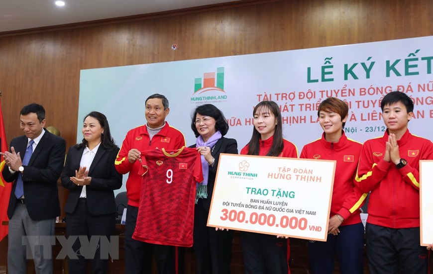  HLV trưởng tuyển bóng đá nữ Việt Nam Mai Đức Chung tặng Phó Chủ tịch nước Đặng Thị Ngọc Thịnh chiếc áo đấu có chữ ký các tuyển thủ tại buổi lễ. (Ảnh: Thành Đạt/TTXVN)