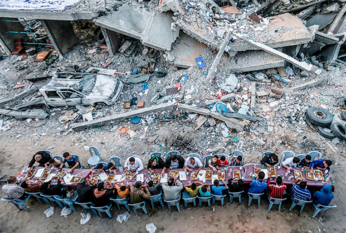 Các gia đình Palestine ăn uống cạnh một tòa nhà bị phá hủy trong cuộc giao tranh giữa lực lượng Hamas và Israel ở Dải Gaza ngày 18/5, trong tháng Ramadan của người Hồi giáo. Ảnh: Mahmud Hams/AFP