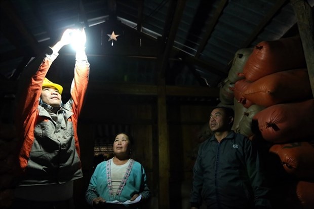 A worker at Muong Nhe District Electricity in the northern mountainous Dien Bien province shows local residents in Hua Sin 1 Village how to change a light bulb (Photo: VNA)