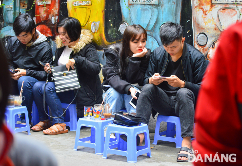 A pavement coffee shop is crowded with young people