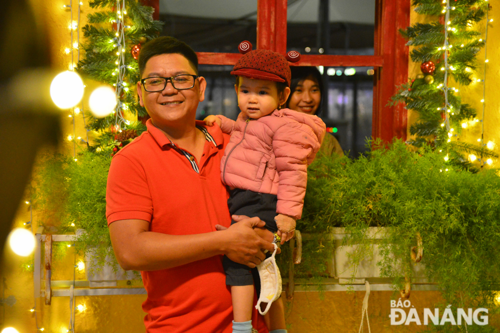 A young man with his son posing for a Christmas photo in a joyful ambience