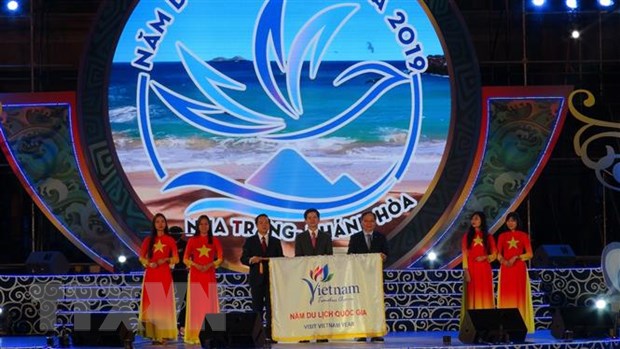 Thứ trưởng Bộ Văn hóa, Thể thao và Du lịch ( giữa) và Lãnh đạo Ủy ban Nhân dân tỉnh Khánh Hòa (phải) trao cờ đăng cai Năm Du lịch quốc gia 2020 cho tỉnh Ninh Bình (bên trái). (Ảnh: Phan Sáu/TTXVN)