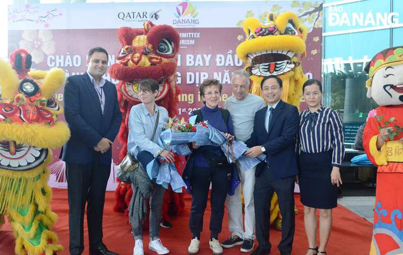 Deputy Director of the municipal Department of Tourism Nguyen Xuan Binh (2nd right) presenting flowers to first international air passengers