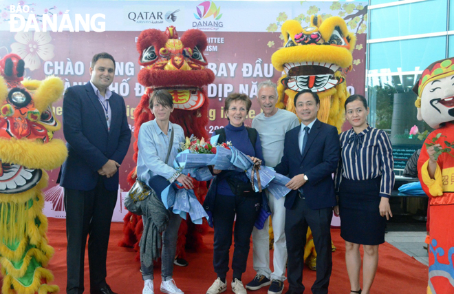 Deputy Director of the municipal Department of Tourism Nguyen Xuan Binh (2nd right) presenting flowers to the foreign first footers.