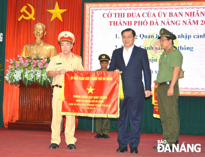 Chủ tịch UBND thành phố Huỳnh Đức Thơ trao Cờ thi đua cho Phòng Cảnh sát giao thông.  	              Ảnh: NGỌC PHÚ