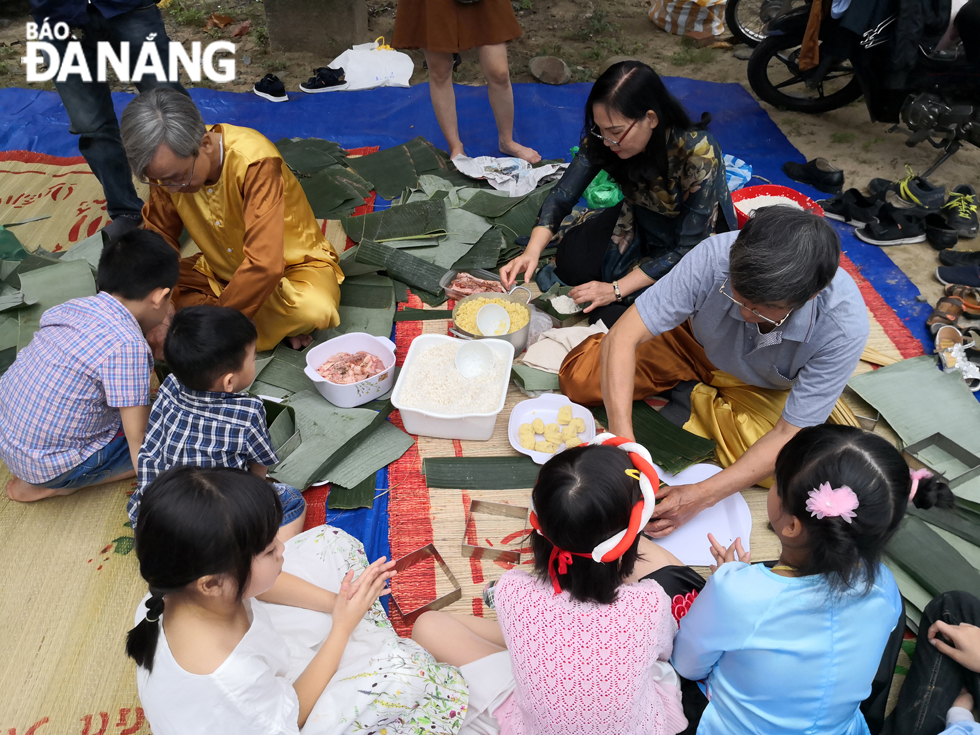 Children learning how to make ‘banh chung’ (square glutinous rice cake) under the guidance of experienced artisans