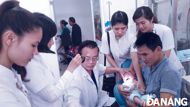 Bác sĩ Nguyễn Văn Đẩu (giữa) đang khám cho trẻ em tại Đà Nẵng.Ảnh: PHAN CHUNG