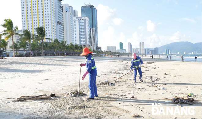 Công nhân Công ty CP Môi trường đô thị Đà Nẵng đang nỗ lực thu dọn rác cho bãi biển sạch đẹp. Ảnh: NAM TRÂN