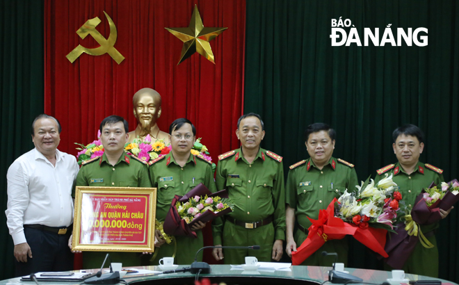 Đại tá Trần Mưu (thứ 3 từ phải sang) và ông Lê Anh (thứ 1 bên trái) trao thưởng nóng 30 triệu đồng cho Công an quận Hải Châu.