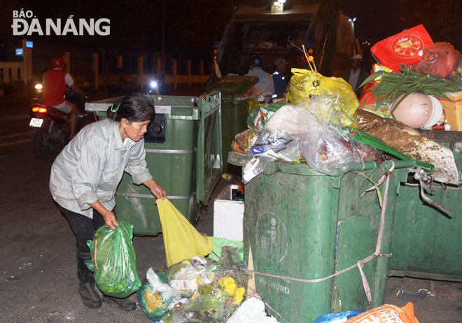 Công nhân Xí nghiệp Môi trường Sơn Trà thu dọn rác trong tối 30 Tết. Ảnh: Hoàng Hiệp