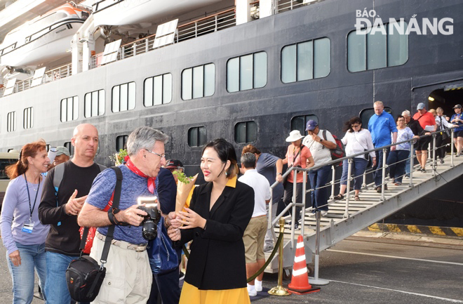 Đại diện Sở Du lịch tăng hoa và chúc tết các hành khách trên chuyến tàu du lịch biển đầu tiên cập cảng Tiên Sa trong Tết Canh Tý. Ảnh: HOÀNG HIỆP