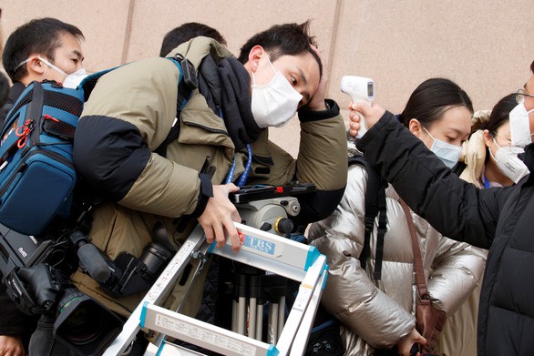Kiểm tra nhiệt độ của các phóng viên tham dự họp báo về tình hình virus corona mới tại Bắc Kinh ngày 26-1. Ảnh: Reuters.