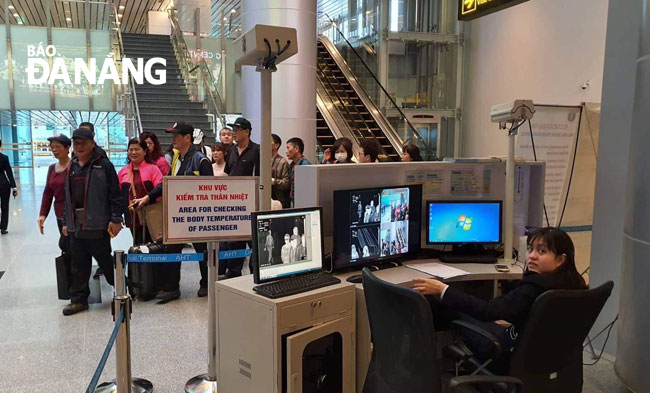 A customs official checks body temperature of passengers at Da Nang International Airport