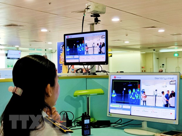 Nhân viên sân bay Tân Sơn Nhất theo dõi trên màn hình hiển thị máy quét thân nhiệt đối với hành khách quốc tế đến Việt Nam. (Ảnh: Đinh Hằng/TTXVN)