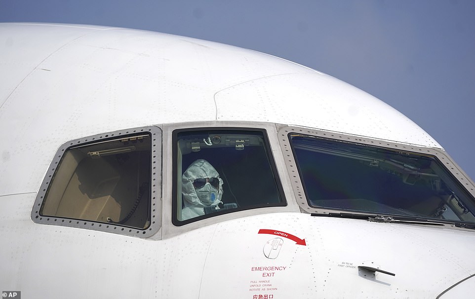 Phi công mặc bộ đồ bảo hộ kín mít trên một chiếc máy bay vận tải tại sân bay quốc tế Thiên Hà Vũ Hán ngày 28-1. Ảnh: AP