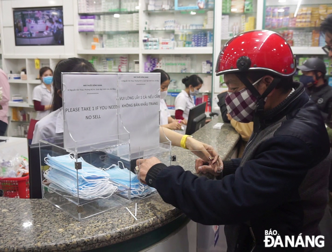 A local resident taking a free face mask at the Dong Giang Pharmacy, located at 32 Nguyen Van Thoai Street in Ngu Hanh Son District's My An Ward