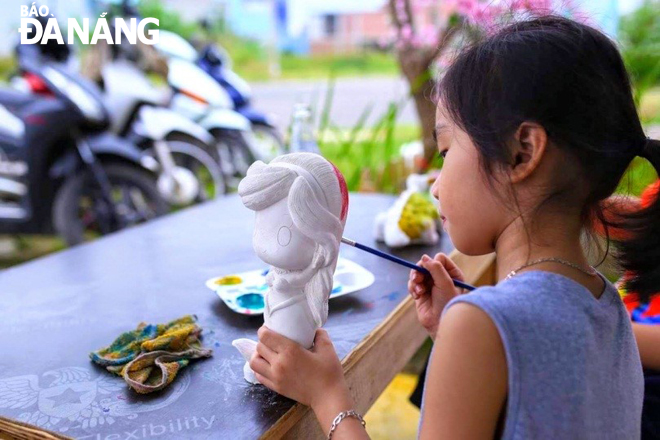 A little girl painting colours on a small plaster statue
