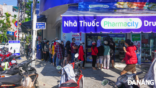 People line up in front of a drugstore which is selling face masks and hand washing liquid at stabilised prices