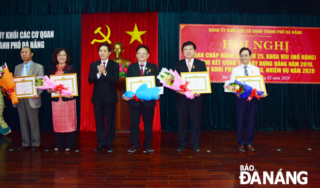 Bí thư Đảng ủy khối Các cơ quan thành phố Phạm Tấn Xử (thứ ba, từ trái sang) trao Huy hiệu Đảng cho các đảng viên đủ tiêu chuẩn.Ảnh: TRỌNG HUY