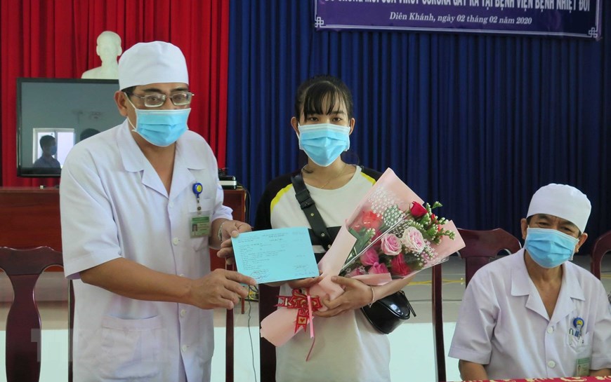 Phó Giám đốc Bệnh viện Bệnh Nhiệt đới Khánh Hòa Nguyễn Vũ Quốc Bình tặng hoa và trao giấy xuất viện cho bệnh nhân Lê Thị Thu H đã bình phục sau thời gian điều trị bệnh nCoV. (Ảnh: Phan Sáu/TTXVN)