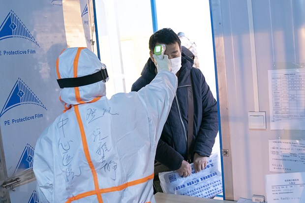 Nhân viên y tế kiểm tra thân nhiệt cho bệnh nhân nhiễm Covid-19 tại một bệnh viện dã chiến ở Vũ Hán, Trung Quốc ngày 5/2/2020. (Nguồn: THX/TTXVN)