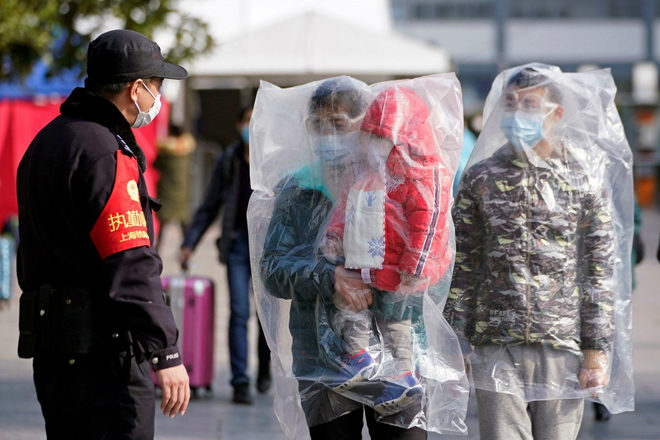 Hành khách đi tàu hỏa tại Thượng Hải (Trung Quốc) mang khẩu trang và dùng nilon phủ lên người để phòng Covid-19. 	   					  Ảnh: Reuters