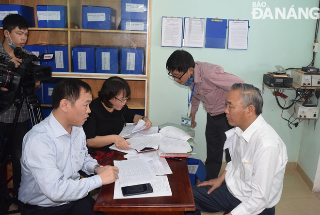 Thứ trưởng Bộ Nông nghiệp và Phát triển nông thôn Phùng Đức Tiến (bìa phải) nghe báo cáo kết quả kiểm tra hồ sơ quản lý truy xuất nguồn gốc hải sản tại cảng cá Thọ Quang. Ảnh: HOÀNG HIỆP