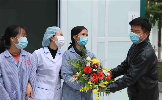Bà Nguyễn Thị T. (cầm hoa) được điều trị khỏi bệnh và xuất viện.