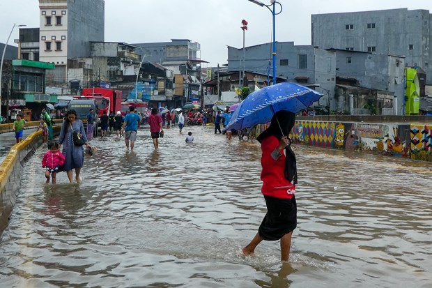 Indonesians wade into floodwater on a street in Jakarta on February 25 (Photo: AFP/VNA)