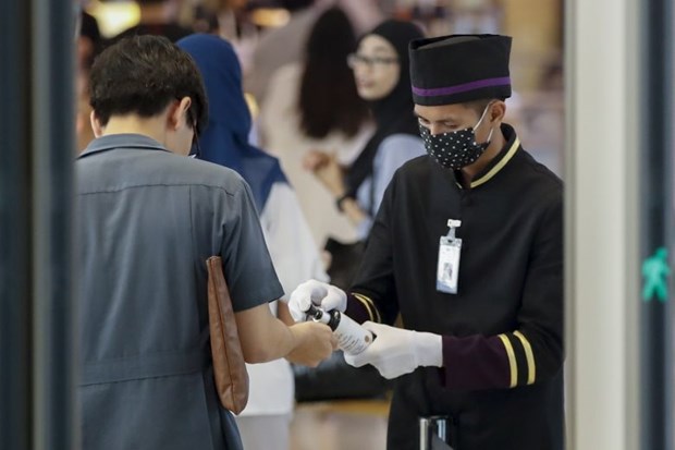 A staff member offers disinfectant to shoppers at the entrance to a department store in Bangkok, Thailand, on Feb 25 (Photo: EPA-EFE)