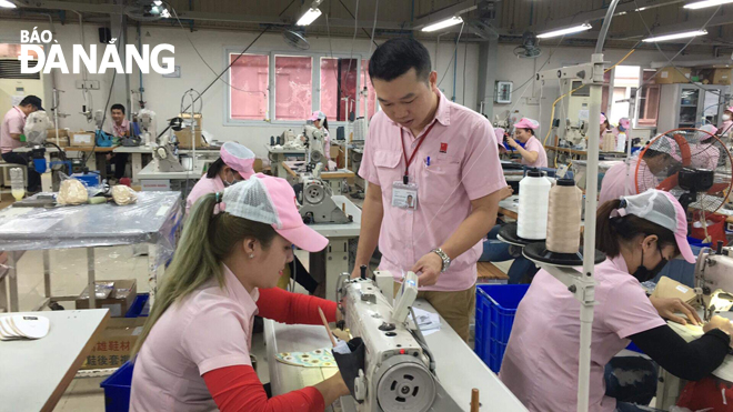 Anh Hoàng Xuân Nhật (giữa) hướng dẫn kỹ thuật cho công nhân thao tác trên sản phẩm tại phân xưởng. 						         Ảnh: NGỌC YẾN