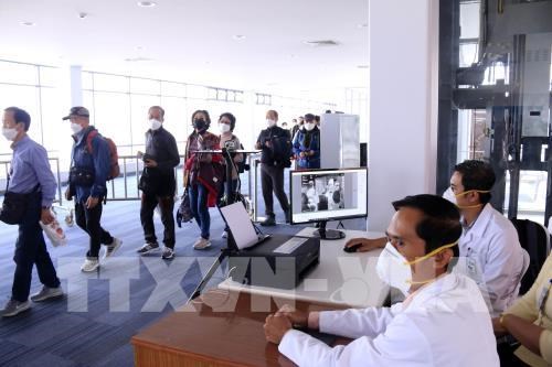 Passengers undergo temperature checks at a border gate in Laos (Photo: VNA)