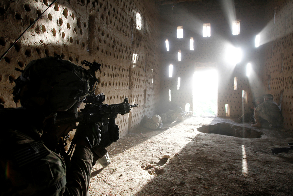 Một binh sĩ Mỹ chĩa súng ra cửa sau khi bị Taliban tấn công lúc đi tuần ở huyện Zharay, tỉnh Kandahar, Afghanistan ngày 26-4-2012. Ảnh: China Daily