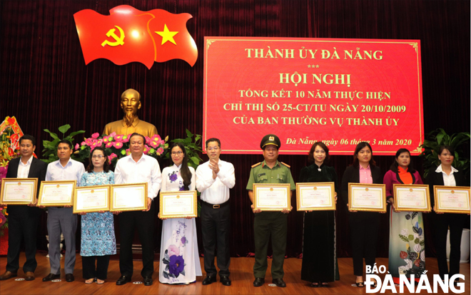 Phó Bí thư Thường trực Thành ủy Nguyễn Văn Quảng (thứ sáu, trái sang) trao bằng khen cho các tập thể đạt thành tích nổi bật trong công tác phòng, chống bạo lực gia đình.      Ảnh: NGỌC HÀ