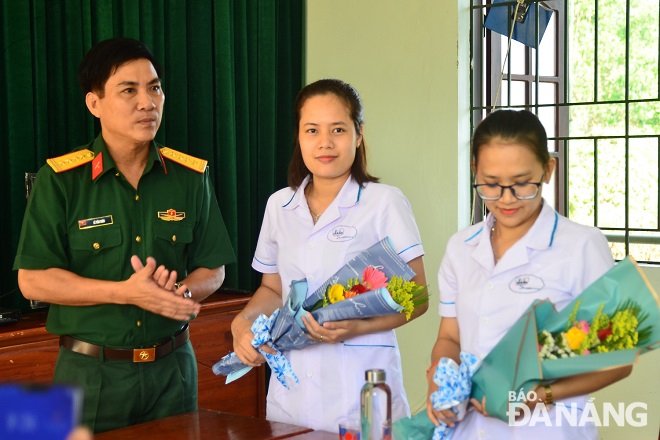 Col Le Van Chin (left) presenting flowers to female medical workers at the Dong Nghe Training Centre, and …