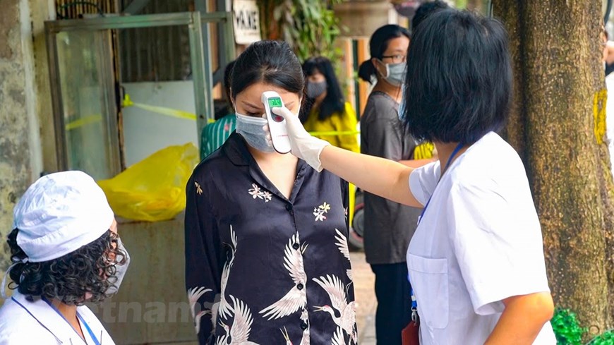 Từ 7h sáng, nhân viên y tế khu vực đã đến để đo thân nhiệt cho người dân xung quanh khu vực cách ly. (Ảnh: Minh Hiếu/Vietnam+)