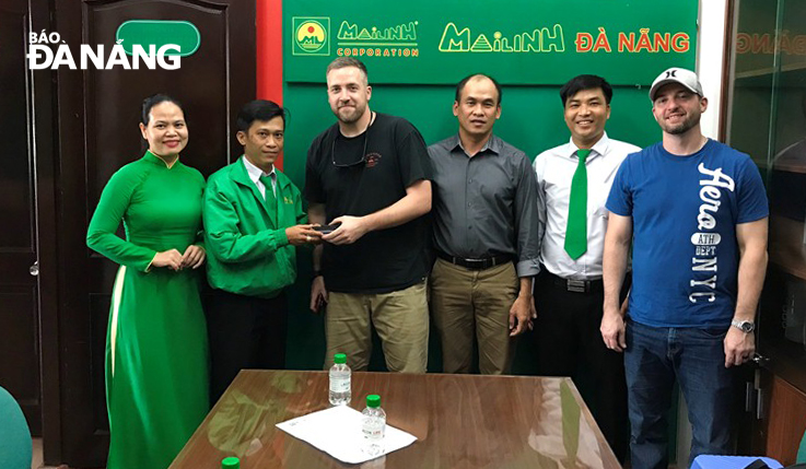 The Mai Linh Taxi Company representatives returning the lost property to the foreigner