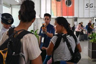 Airport personnel checking the temperature of a passenger at the departure area of the international airport in Manila (Source: AFP)