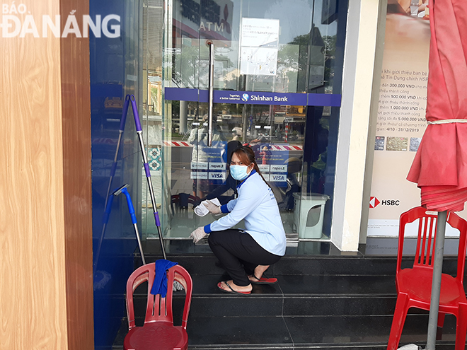 Nhân viên vệ sinh đang lau chùi tại một trụ sở trên đường Nguyễn Văn Linh vào sáng 11-3. Ảnh: KHÁNH HÒA