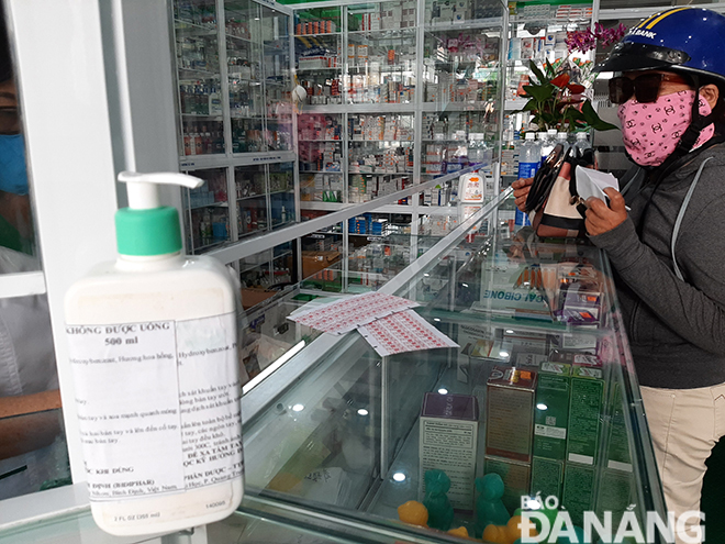 Một quầy thuốc trên đường Hoàng Diệu (quận Hải Châu) khuyến cáo khách hàng sử dụng dung dịch vệ sinh để rửa tay trước khi thực hiện giao dịch. Ảnh: KHÁNH HÒA