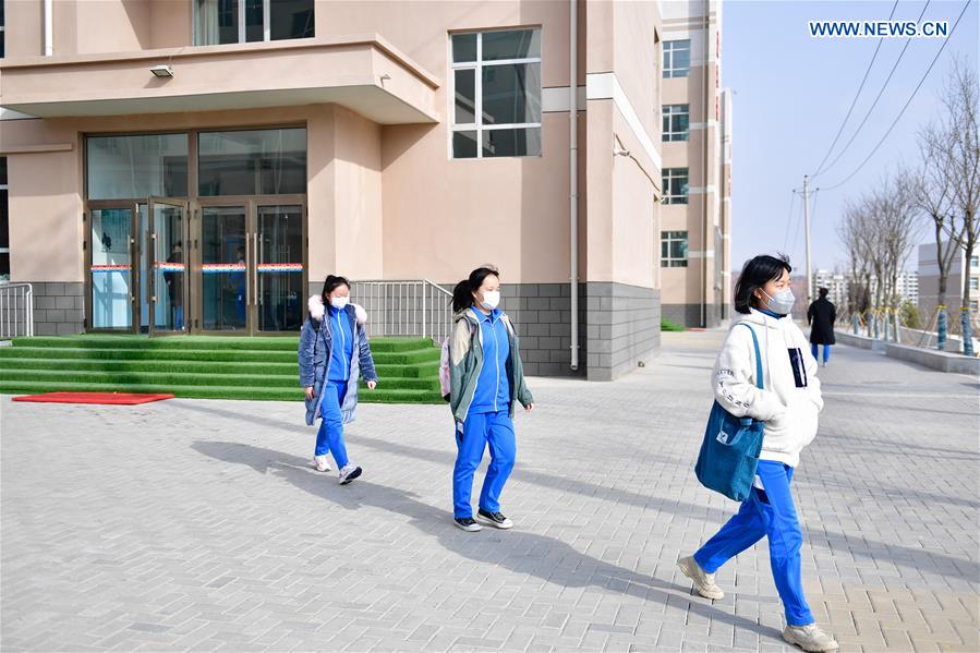 Các em học sinh tại trường trung học phổ thông Hải Đông ở tỉnh Thanh Hải đeo khẩu trang đi bộ qua sân trường. Ảnh: THX