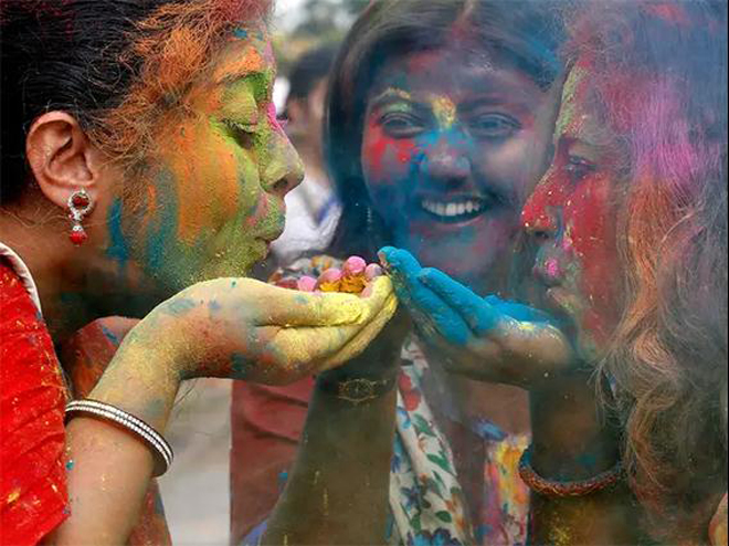 Những người tham gia lễ hội Holi chuẩn bị thổi bột màu vào không trung.