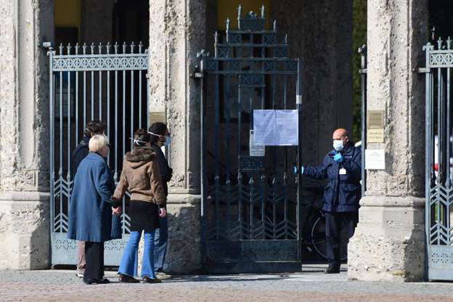 Một người đóng cổng nghĩa trang Bergamo khi người thân của người quá cố đứng bên ngoài. Ảnh: AP