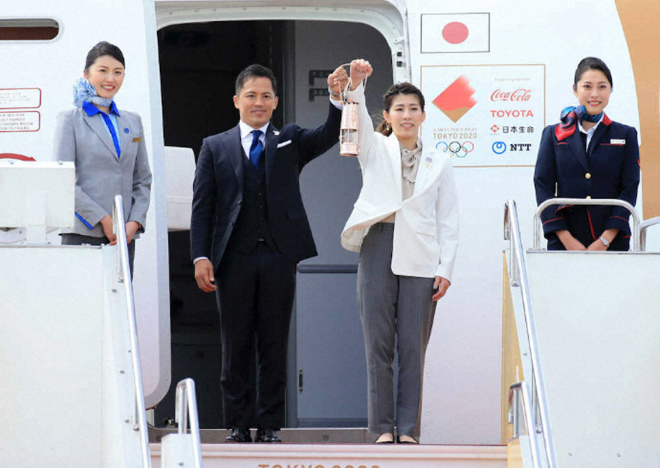 Ngọn lửa Olympic đã đến Nhật Bản, được 2 VĐV Tadahiro Nomura (trái) và Saori Yoshida (phải) tiếp nhận trong không khí rất lặng lẽ. Ảnh: SPONOCHI