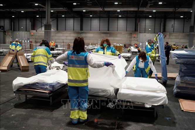 Nhân viên y tế chuẩn bị giường cho bệnh nhân tại bệnh viện dã chiến ở Madrid, Tây Ban Nha, ngày 22-3. Ảnh:THX/TTXVN