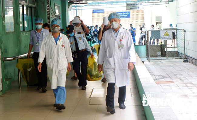 Nhân viên y tế Bệnh viện Đà Nẵng dẫn các bệnh nhân bằng lối cách ly riêng ra xe chuyên dụng đưa các bệnh nhân về nơi cư trú. Ảnh: PHAN CHUNG