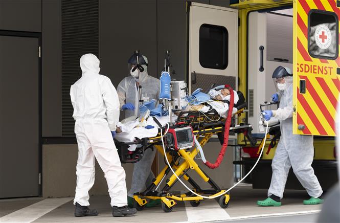Nhân viên y tế chuyển bệnh nhân mắc COVID-19 từ xe cứu thương vào một bệnh viện ở Dresden, Đức ngày 26/3/2020. Ảnh: AFP/TTXVN