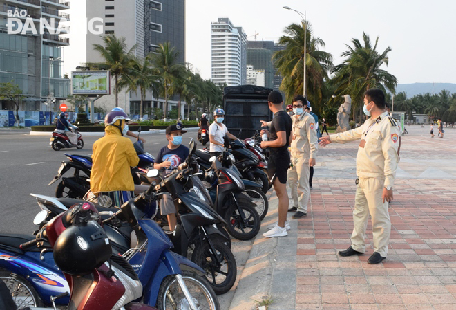 Lực lượng Kiểm tra quy tắc đô thị quận Sơn Trà nhắc nhở, vận động người dân chấp hành chủ trương của UBND thành phố về tạm dừng các hoạt động liên quan đến tắm biển. Ảnh: HOÀNG HIỆP