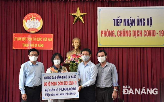 Chủ tịch Uỷ ban MTTQ Việt Nam thành phố Đặng Thị Kim Liên (thứ 2, trái qua) tiếp nhận kinh phí ủng hộ từ đại diện Trường Cao đẳng nghề Đà Nẵng. Ảnh: TRẦN KHANG